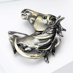 Détail d'une broche tête de cheval vintage en métal avec œil en pierre verte