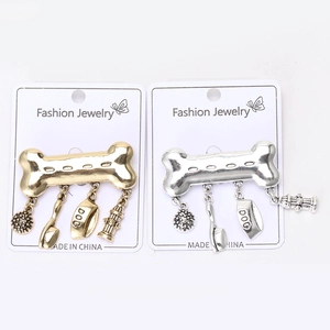 Detail view of retro alloy bone brooches in gold and silver with dog theme pendants