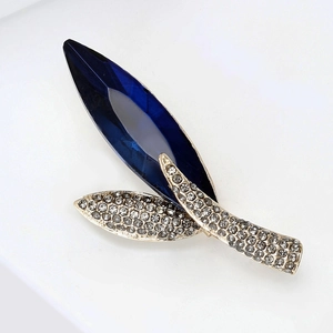 Detail view of leaf brooch with large marquise-cut navy blue stone and gold plating