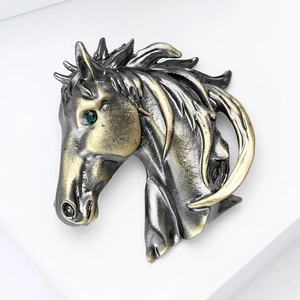 Détail d'une broche tête de cheval avec textures bicolores et œil en pierre verte