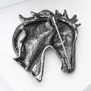 Détail macro d'une broche tête de cheval en alliage montrant la texture et l'attache