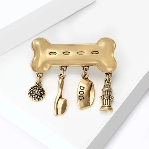 Vintage gold bone brooch with dog bowl and fire hydrant charms on a minimalist pedestal