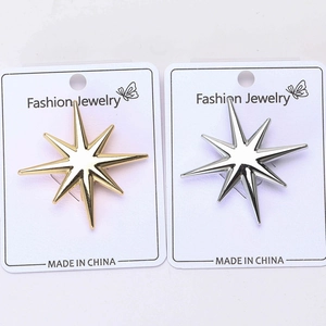 Broches étoiles à huit branches en or et argent polies sur une carte de bijoux