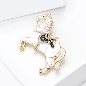 Close-up of a gold horse brooch with white enamel and sparkling rhinestones on saddle