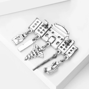 Macro detail of vintage silver house brooch with industrial pendants on white display