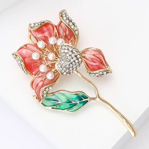 Détail macro de broche fleur en émail avec pétales roses, cristaux et perles sur or