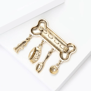 Vintage gold bone brooch with dog charm pendants on a minimalist white background