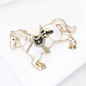 Detailed close-up of a silver horse brooch with white enamel and sparkling rhinestones