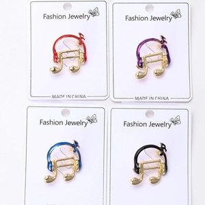 Macro detail of music-themed enamel brooch pins featuring headphones and musical notes