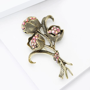 Dettaglio macro della spilla tulipano con strass rosa cangianti e trama in oro vintage