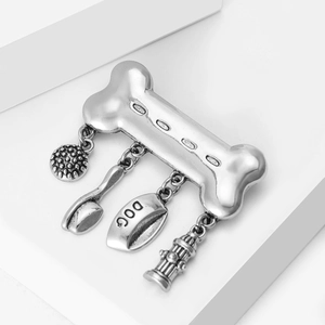 Vintage silver dog bone brooch with hanging charms including a bowl and hydrant