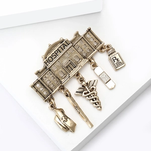 Vintage gold hospital themed brooch with medical charms like Rx bottle and caduceus