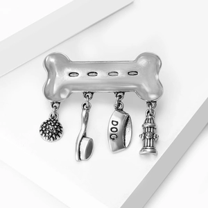 Close-up of vintage silver dog bone brooch with four unique pet-themed dangling charms