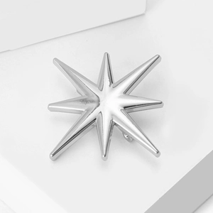Détail macro d'une broche étoile argentée polie sur un présentoir blanc épuré