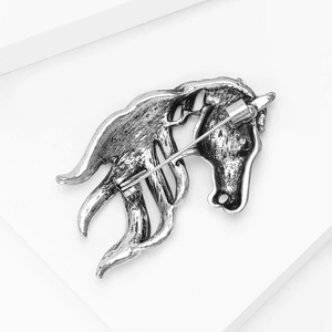 Macro view showing the vintage silver alloy back structure and safety pin of the horse brooch