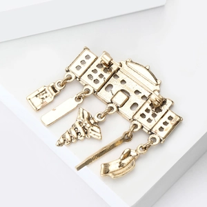 Detail of vintage gold medical brooch with antique pendants and secure safety pin clasp