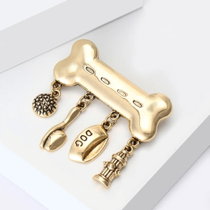 Detailed close-up of a vintage gold bone brooch with dangling dog bowl and hydrant charms
