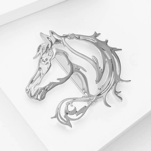 Macro di una spilla a testa di cavallo argento su supporti geometrici bianchi minimali