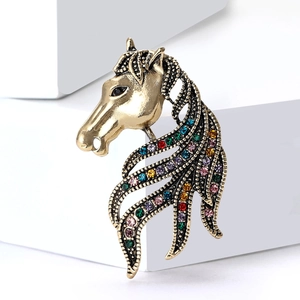 Macro shot of horse head brooch featuring colorful inlaid rhinestones on vintage gold metal