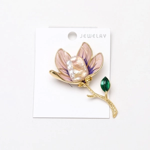 Macro detail of magnolia brooch featuring pink enamel petals and a baroque pearl center