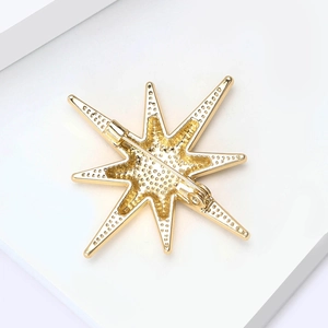 Vue arrière d'une broche étoile à huit branches dorée montrant le fermoir et la texture
