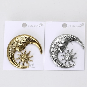 Detail of sun and crescent moon face brooches in gold and silver stainless steel finish