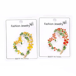 Détail de broches florales en forme de cœur avec perles rouges et jaunes et strass verts