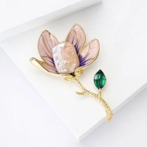 Elegant magnolia flower brooch with baroque pearl and enamel on a white stand
