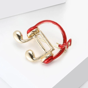 Detail of red enamel music note headphone brooch with elegant gold plating finish