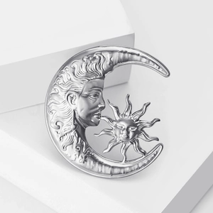 Macro detail of silver moon and sun brooch with polished metallic celestial relief