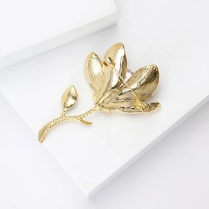 Close-up of golden magnolia brooch with brushed metal texture and pin fastener back