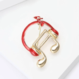 Macro detail of red headphone and golden music note brooch with fine enamel finish