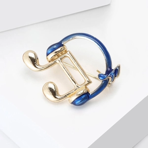Macro detail of music note brooch with blue enamel inlay and gold metallic finish