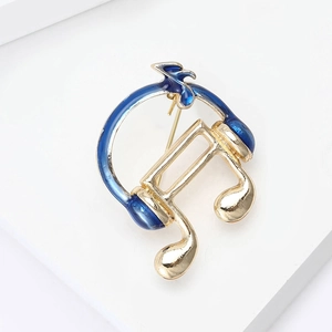 Macro detail of headphone and music note brooch with blue enamel and gold finish