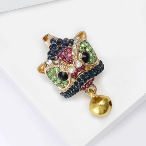 Chinese lion dance brooch with colorful rhinestones and gold bell on a white display