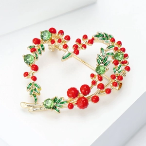 Détail de la broche de Noël en forme de cœur avec baies rouges et cristaux verts