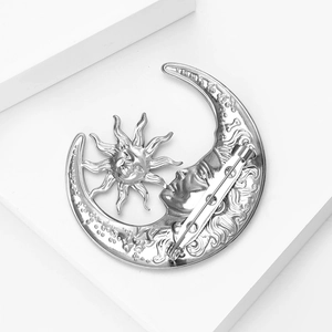 Detailed close-up of a vintage silver moon and sun brooch with textured relief carvings