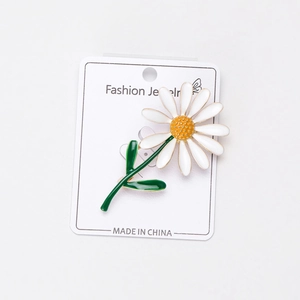 Vue détaillée d'une broche marguerite blanche avec centre jaune sur sa carte