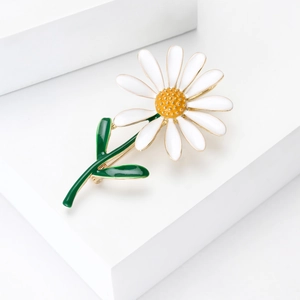 Élégante broche fleur marguerite avec pétales en émail blanc et placage or sur fond blanc