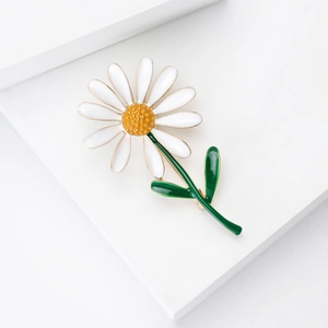 Détail d'une broche marguerite en émail blanc avec centre texturé jaune vif