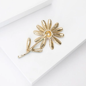 Broche marguerite dorée avec pétales en émail poli et tige élégante sur socle blanc