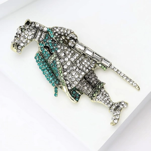 Close-up of vintage horse knight shield brooch with green zircons and gold finish