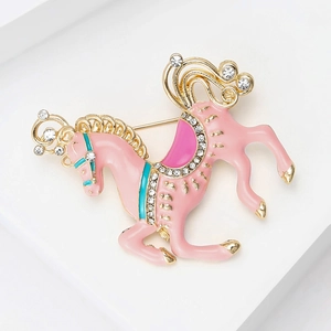 Close-up of pink enamel carousel horse brooch with sparkling rhinestones on golden alloy