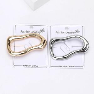 Detailed macro view of polished gold and silver irregular round metal brooches on cards