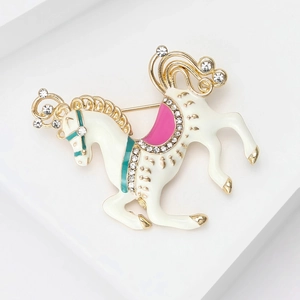Close-up of elegant white carousel pony brooch with sparkling rhinestones and gold accents