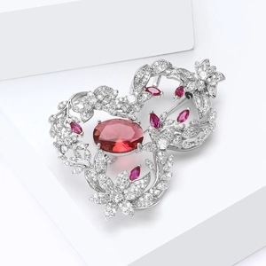 Détail d'une broche florale en argent ornée d'un grand rubis rouge ovale et de zircons