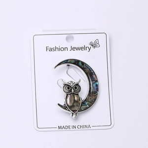 Macro view of owl brooch with shimmering abalone shell inlays on a crescent moon design