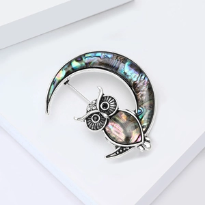 Elegant owl and crescent moon brooch with abalone shell inlay on white geometric background