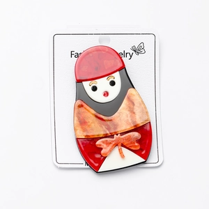 Détail d'une broche poupée russe en acrylique coloré sur une carte de bijoux blanche