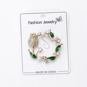 Detailed close-up of a luxury golden tulip wreath brooch with pearls and green enamel